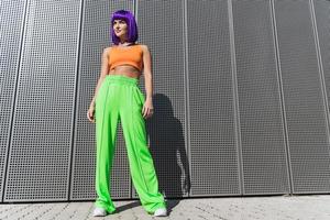 jovem vestindo roupas esportivas coloridas posando na rua durante o dia de verão foto