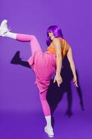 dançarina despreocupada vestindo roupas esportivas coloridas atuando contra fundo roxo foto