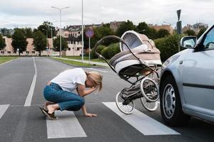 mãe horrorizada na faixa de pedestres após um acidente de carro quando um veículo atinge seu carrinho de bebê. foto