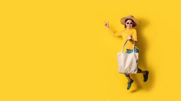retrato de uma garota linda animada usando vestido e óculos escuros, segurando sacolas de compras. jovem alegre com bolsa em fundo amarelo. shopaholic shopping fashion. foto