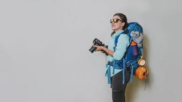 imagem conceitual de uma garota com uma mochila em uma câmera portátil em um fundo branco. mochila de viagem. viajar ao redor do mundo. foto