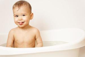 garotinho tomando banho está enfiando a língua em água morna foto