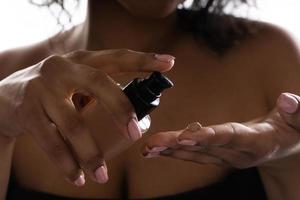 mulher negra segurando garrafa dispensadora com uma base líquida foto