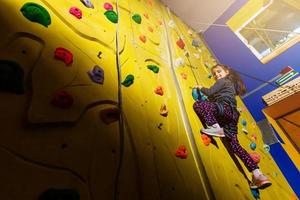 menina escalando uma parede de pedra interior. conceito de vida esportiva. foto