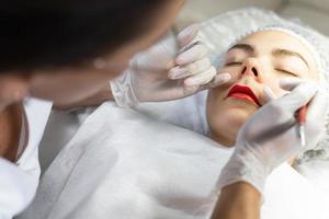 maquiador permanente e seu cliente durante o procedimento de blush labial foto