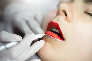 maquiador permanente e seu cliente durante o procedimento de blush labial foto