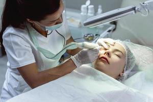 maquiadora permanente e sua cliente durante o tratamento de aprimoramento da linha dos cílios foto