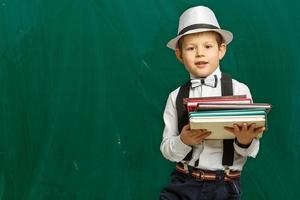 de volta à escola. menino engraçado em óculos apontando para cima no preto foto