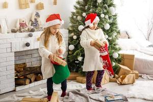 crianças irmãzinhas seguram fundo interior de caixas de presentes. que grande surpresa. pequenas garotas bonitas receberam presentes de feriado. melhores brinquedos e presentes de natal. amigos de crianças animados desembalando seus presentes. foto