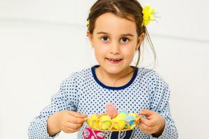 menina sorridente bonitinha com cesta cheia de ovos de páscoa coloridos foto