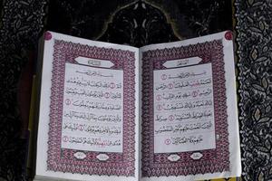 al-quran que está acima do tapete de oração com fundo preto foto