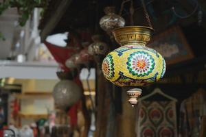 mercado com lâmpadas turcas coloridas tradicionais feitas à mão e lanternas, foco seletivo na lanterna, fundo desfocado, lanternas de souvenirs populares penduradas na loja para venda. foto