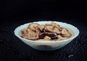 um prato branco de cogumelos em conserva. comida saudável da aldeia. cogumelo de leite preto em conserva. foto