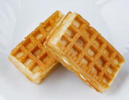 deliciosos waffles vienenses frescos com creme branco estão sobre um prato branco. foto