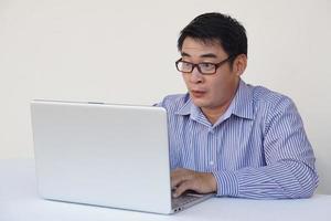 homem asiático se sente surpreso e animado durante a navegação na internet no computador portátil. conceito, expressão emocional. uau. sentimento. trabalho online, trabalhando com dados. foto