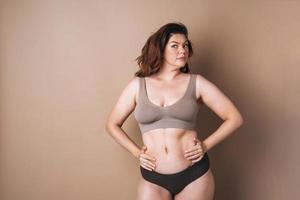 retrato de mulher amorosa plus size em cueca em fundo bege, amor corporal foto