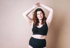 retrato de mulher amorosa plus size em cueca em fundo bege, amor corporal foto