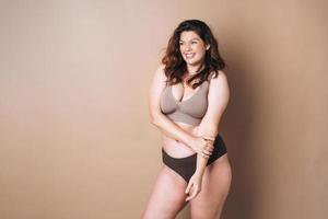 retrato de mulher amorosa plus size em cueca em fundo bege, amor corporal foto