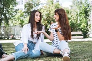jovens lindas garotas asiáticas com cabelos longos em roupas casuais, amigos se divertindo no parque da cidade foto