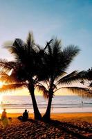 silhueta do belo pôr do sol na praia do mar com palmeira para viajar no tempo de relaxamento de férias, foto