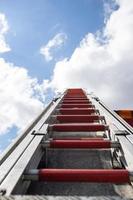escada retrátil em um carro de bombeiros, no contexto de um céu azul e nuvens. vista de baixo. foto