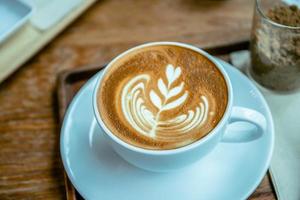 xícara de café com leite com aroma no estilo de café de mesa de madeira foto
