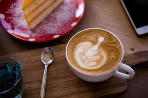 xícara de arte latte com aroma de café e saboroso bolo de natal na mesa de madeira relaxtime no café cafeteria foto