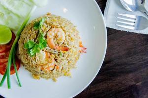 arroz frito com camarão em um prato branco na mesa de madeira em estilo de comida tailandesa foto