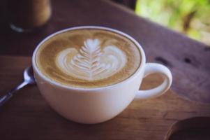 xícara branca de café com leite na mesa de madeira no café café da manhã foto