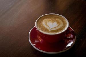 o amor de xícara de café vermelho, café escuro na mesa de madeira escura foto