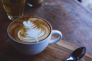 café bebida quente cappucino latte art na mesa vintage de madeira, hora do café no café de fundo de madeira foto