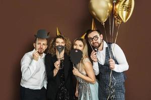 pessoas felizes usando chapéus de festa com adereços de cabine de fotos estão comemorando feriado ou evento