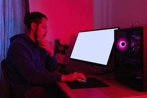 homem trabalhando no pc moderno à noite na sala com luz neon. tela de monitor em branco para design. foto