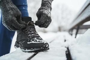 homem corredor está amarrando seus sapatos durante seu treino de inverno foto