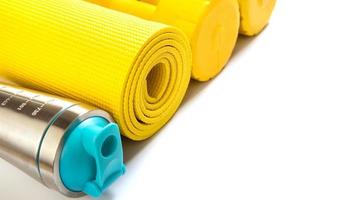 tapete de fitness amarelo e halteres em fundo branco foto