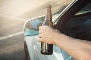 motorista de carro segurando uma garrafa de cerveja foto