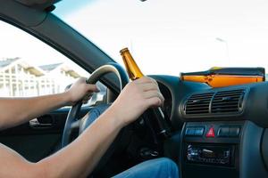 motorista de carro segurando uma garrafa de cerveja foto