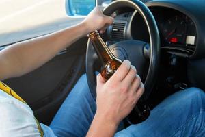 motorista de carro segurando uma garrafa de cerveja foto
