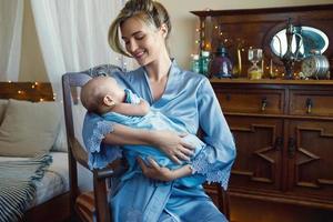 jovem linda mãe com seu bebezinho embrulhado no pano azul foto