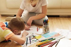 feliz mãe e filho estão desenhando juntos em casa foto