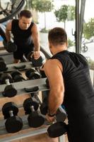 homem exercitando com halteres durante seu treino de musculação no ginásio foto