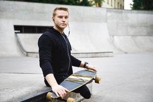 jovem deficiente com um longboard em um skatepark foto