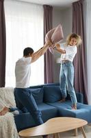 casal feliz durante luta de almofadas em seu apartamento foto