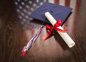 chapéu de formatura e diploma na mesa com reflexão da bandeira americana foto