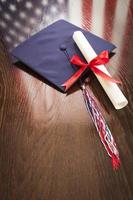 chapéu de formatura e diploma na mesa com reflexão da bandeira americana foto