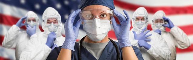 médicos ou enfermeiras usando equipamento de proteção pessoal médico contra a bandeira da bandeira americana foto