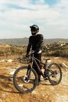 piloto de downhill totalmente equipado com equipamento de proteção e sua bicicleta foto