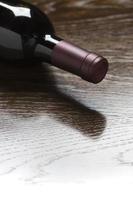 garrafa de vinho tinto deitada na madeira desbotando para branco foto