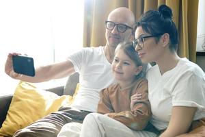 família feliz tomando selfie usando smartphone em casa foto