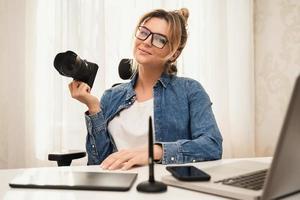 fotógrafa de mulher feliz com uma câmera sem espelho no local de trabalho foto